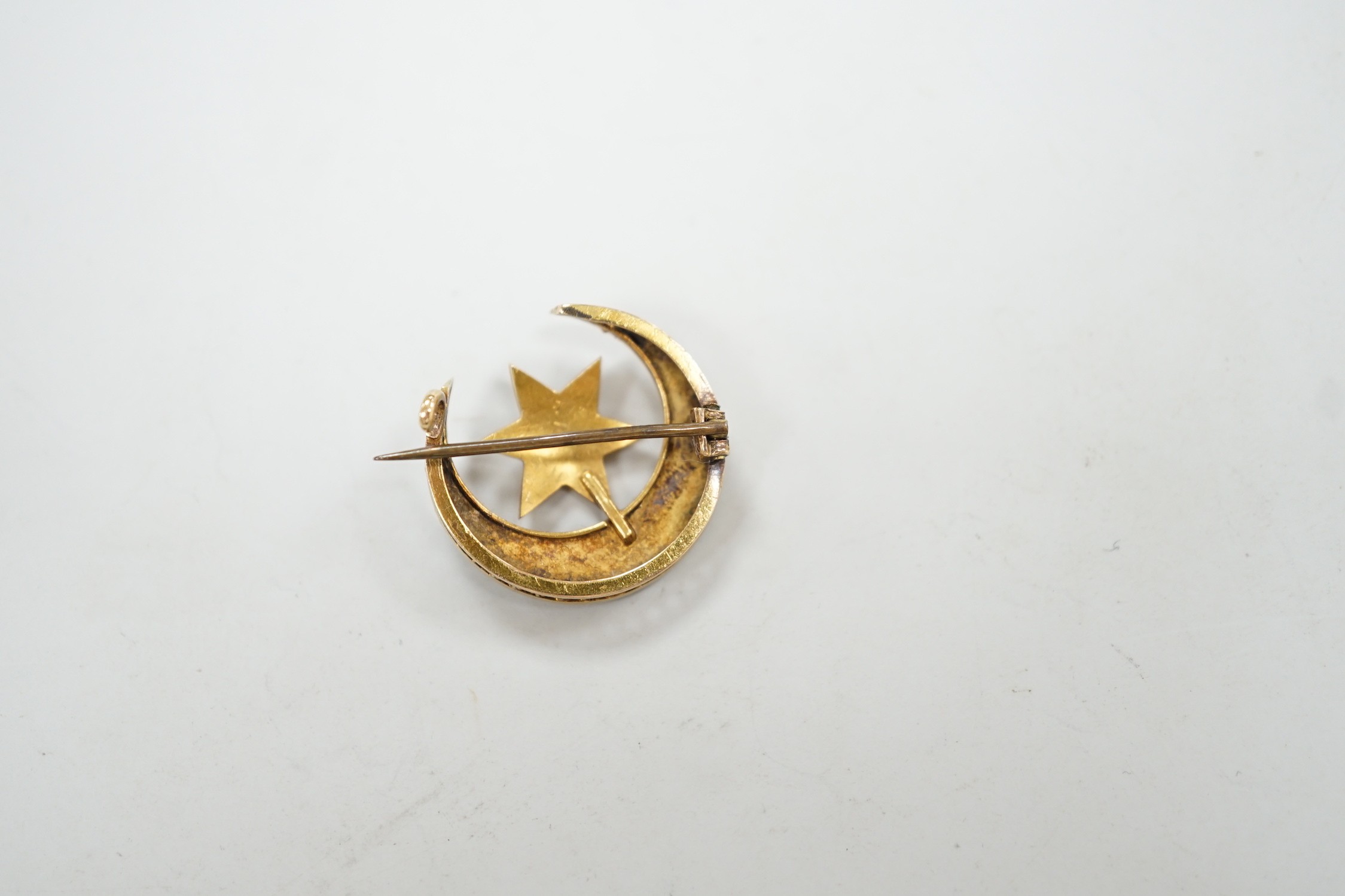 An Edwardian yellow metal and seed pearl set crescent moon and star brooch, 22mm, gross weight 4 grams.